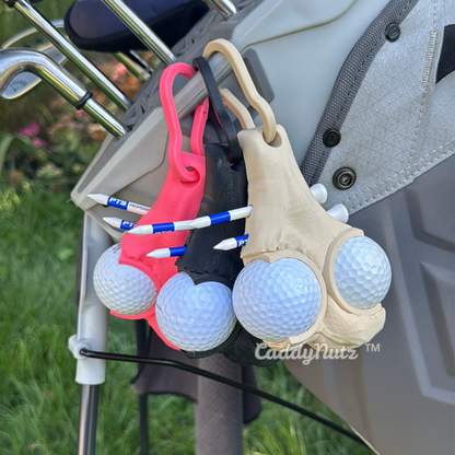 Golf ball holder with golf balls attached to a golf bag on a golf course.