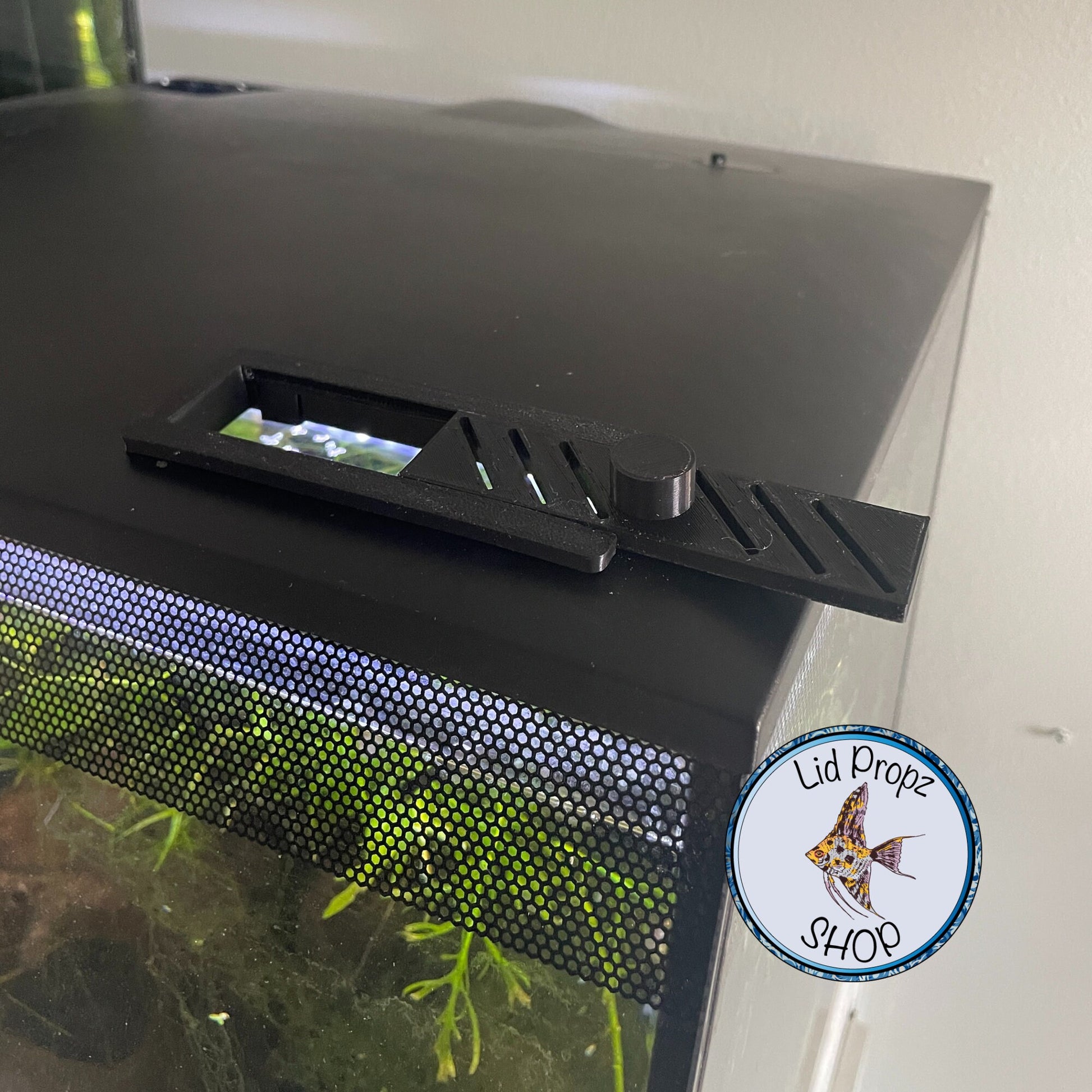 Fluval Flex 9 and 15 gallon feed opening cover with built-in vents, custom 3D printed for a snug fit, shown in sleek black and white finish, prevents evaporation and keeps tank clean. Precision slide-in vented feeding port cover for Fluval Flex aquariums, black and white options available, improves tank aesthetics while allowing airflow and easy access
