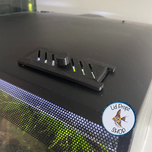 3D printed vented slide cover for Fluval Flex 9 gallon and 15 gallon aquarium feeding opening, shown in black and white, designed for a perfect fit and improved airflow. Vented slide cover installed on Fluval Flex 15G feed hole. Matches lid color and blocks evaporation while allowing airflow. Slides open for easy feeding.